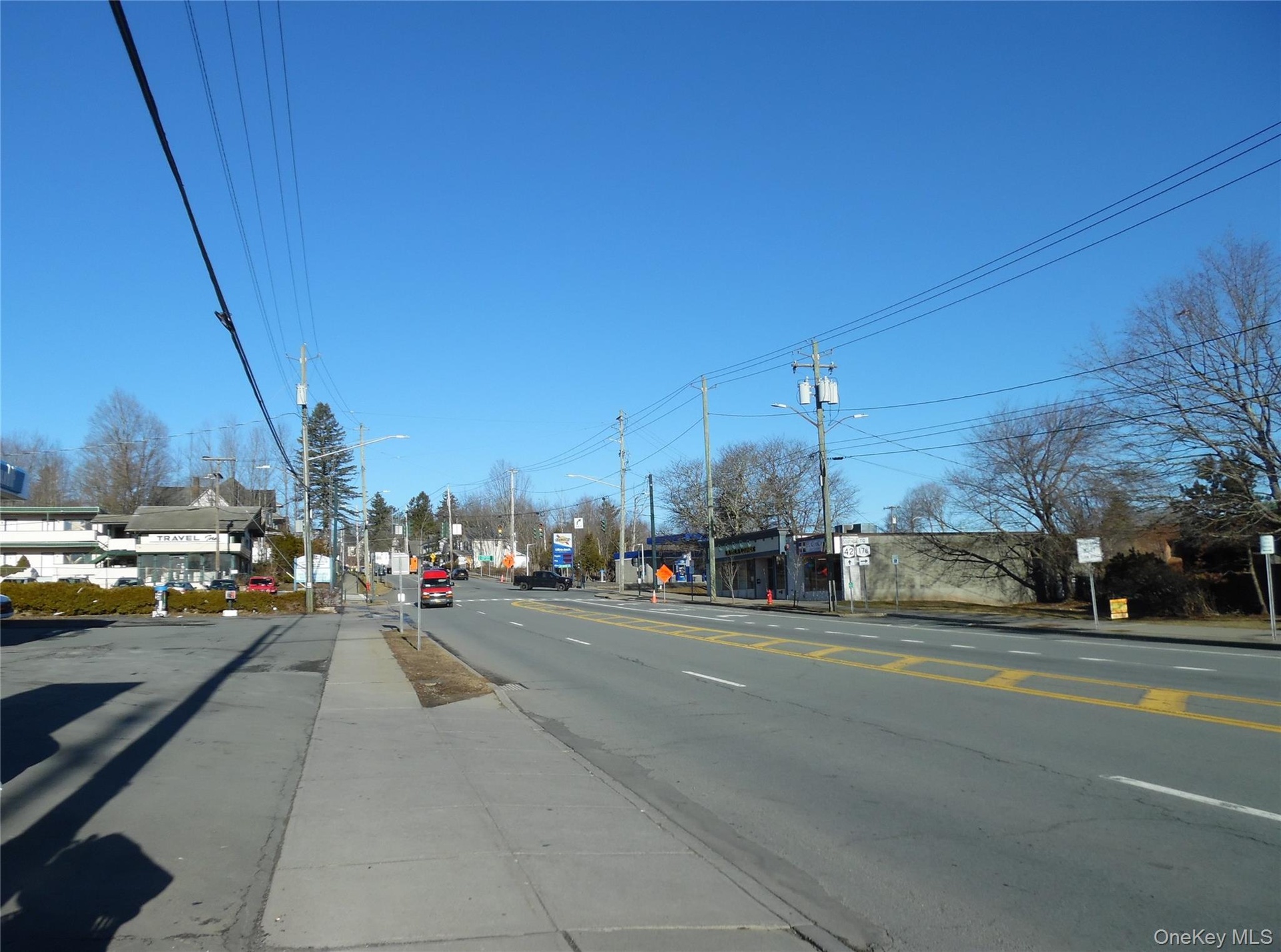 View of asphalt street with sidewalks, curbs, and street lighting