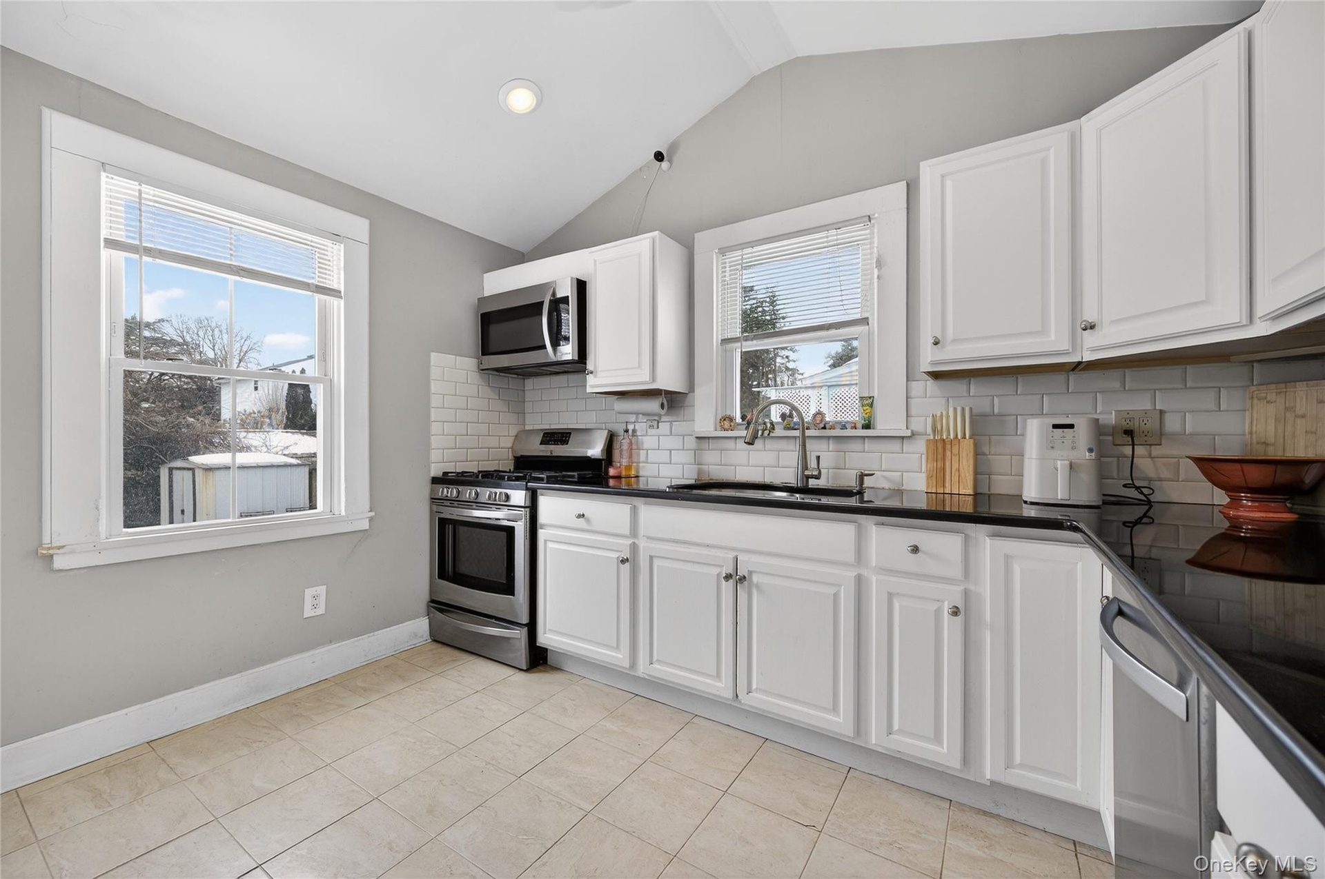 White cabinetry with black granite countertops and subway tile backsplash. Views of the side and backyard.