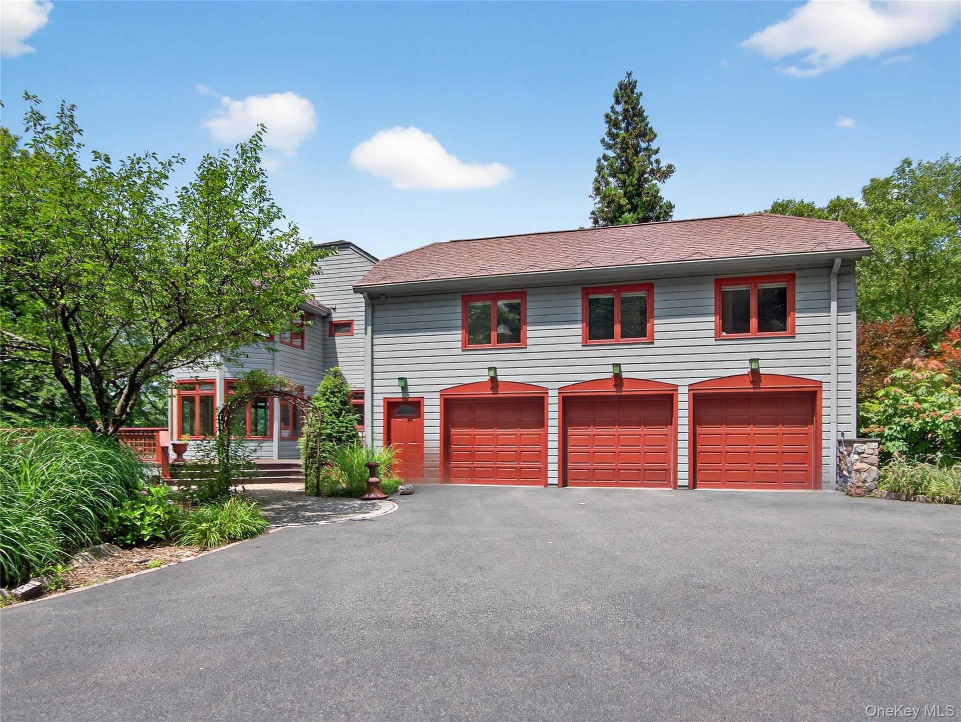 View of front of house featuring asphalt driveway, an attached garage, and roof with shingles