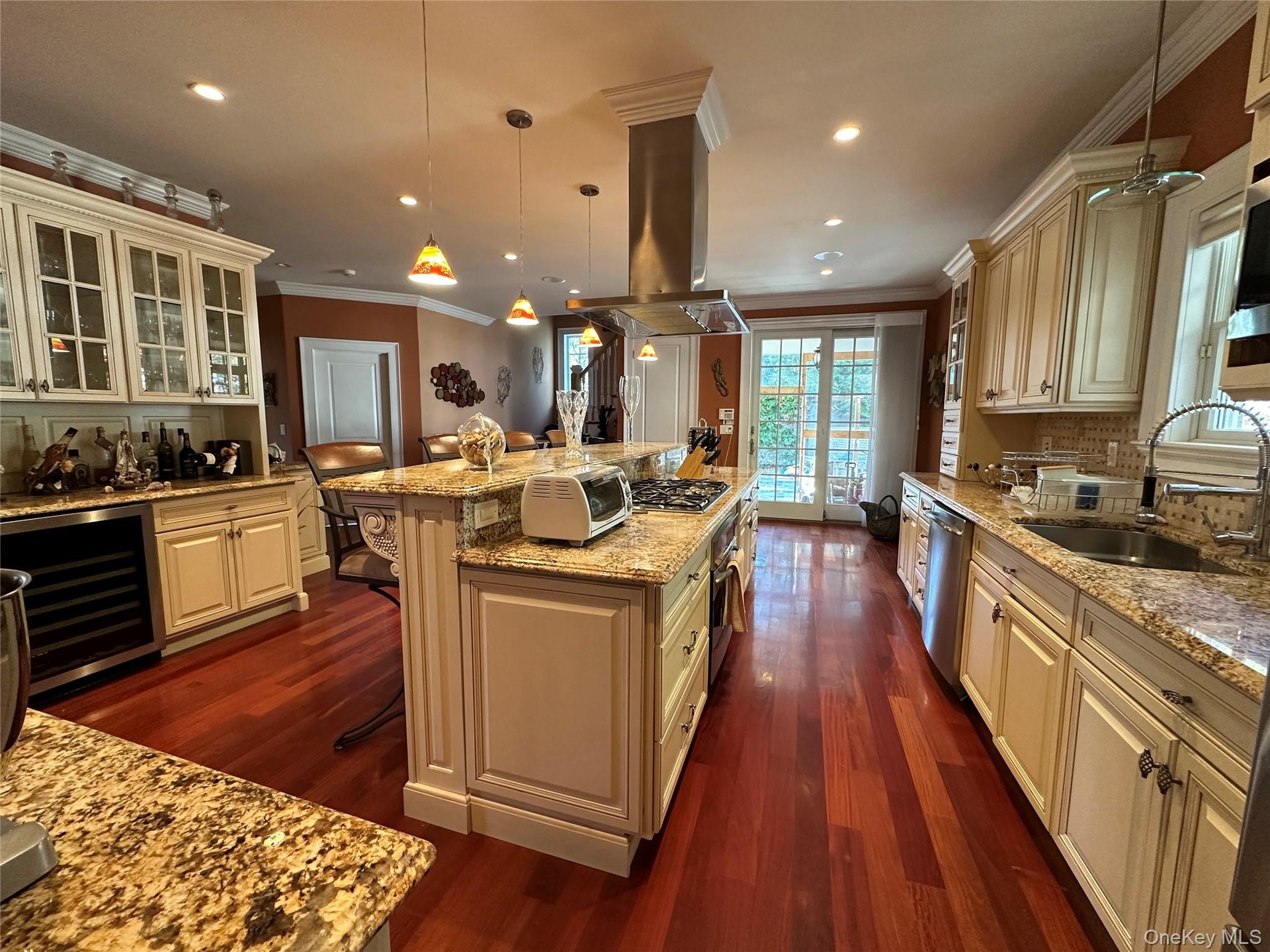 Kitchen with custom  cabinetry, light granite countertops, Turkish marble mosaic backsplash, crown molding, and island range hood, ornamental molding,