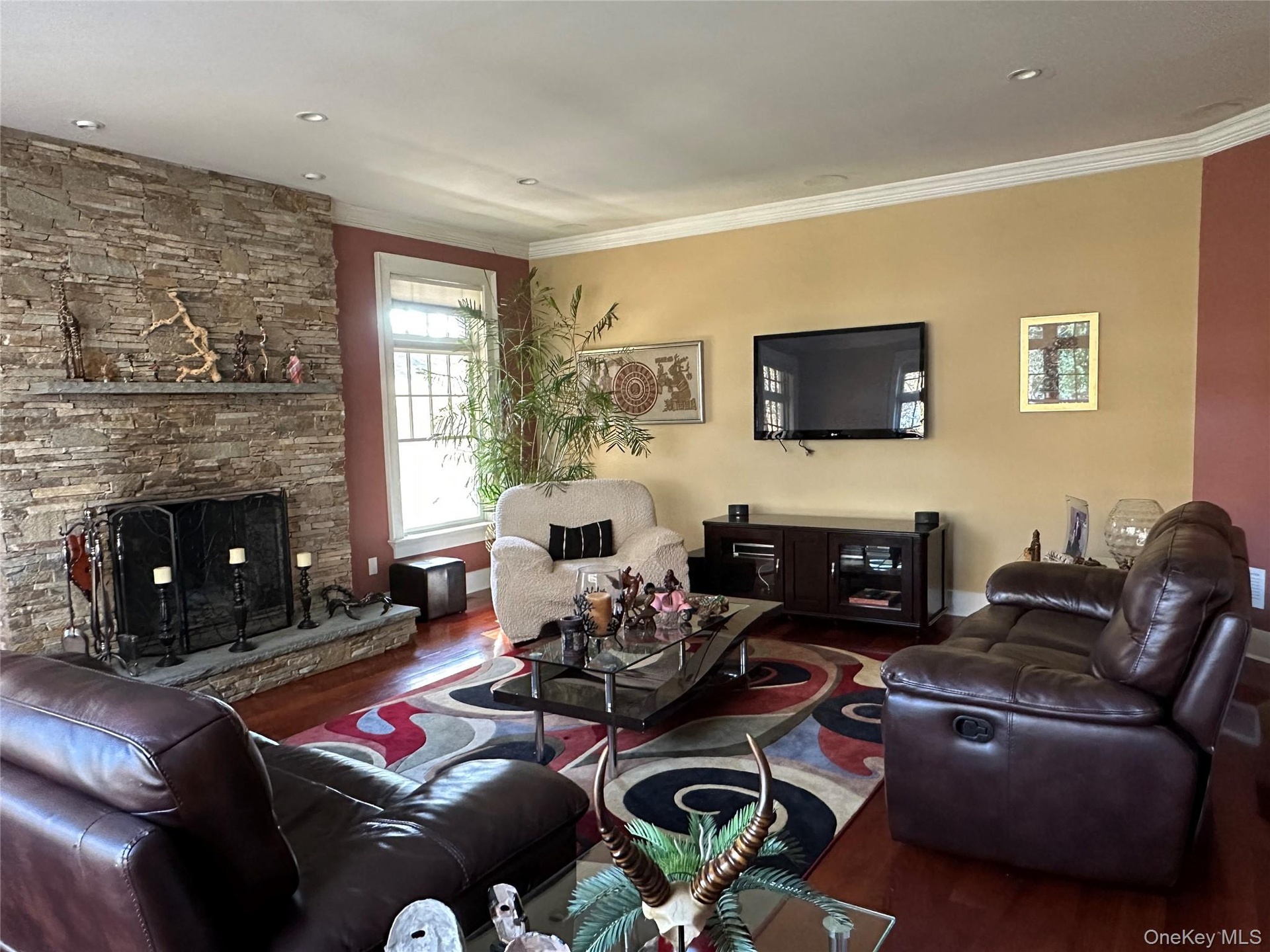 Living room featuring wood finished floors, ornamental molding, and a fireplace