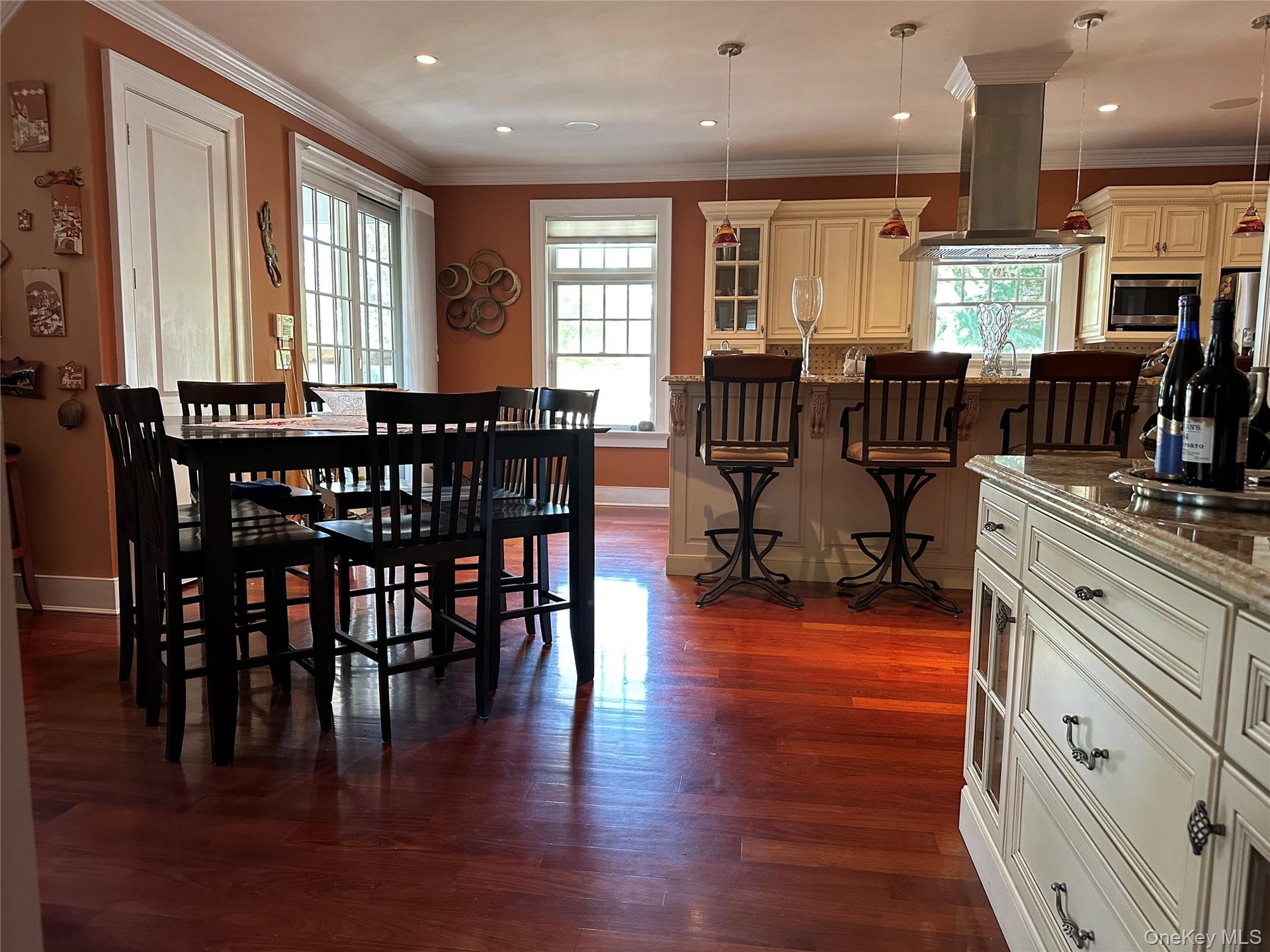Eat-in-kitchen featuring continuous Red Brazilian Mahogony wide plank wood floors, ornamental molding, and recessed lighting