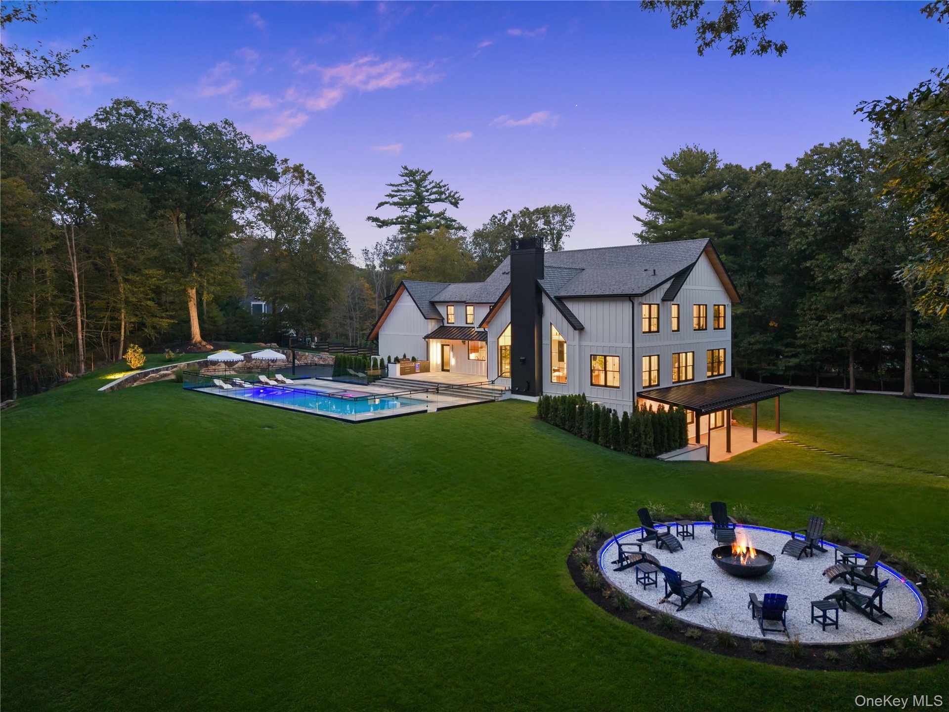 Back of property featuring a patio area, a fire pit, a lawn, a chimney, and board and batten siding