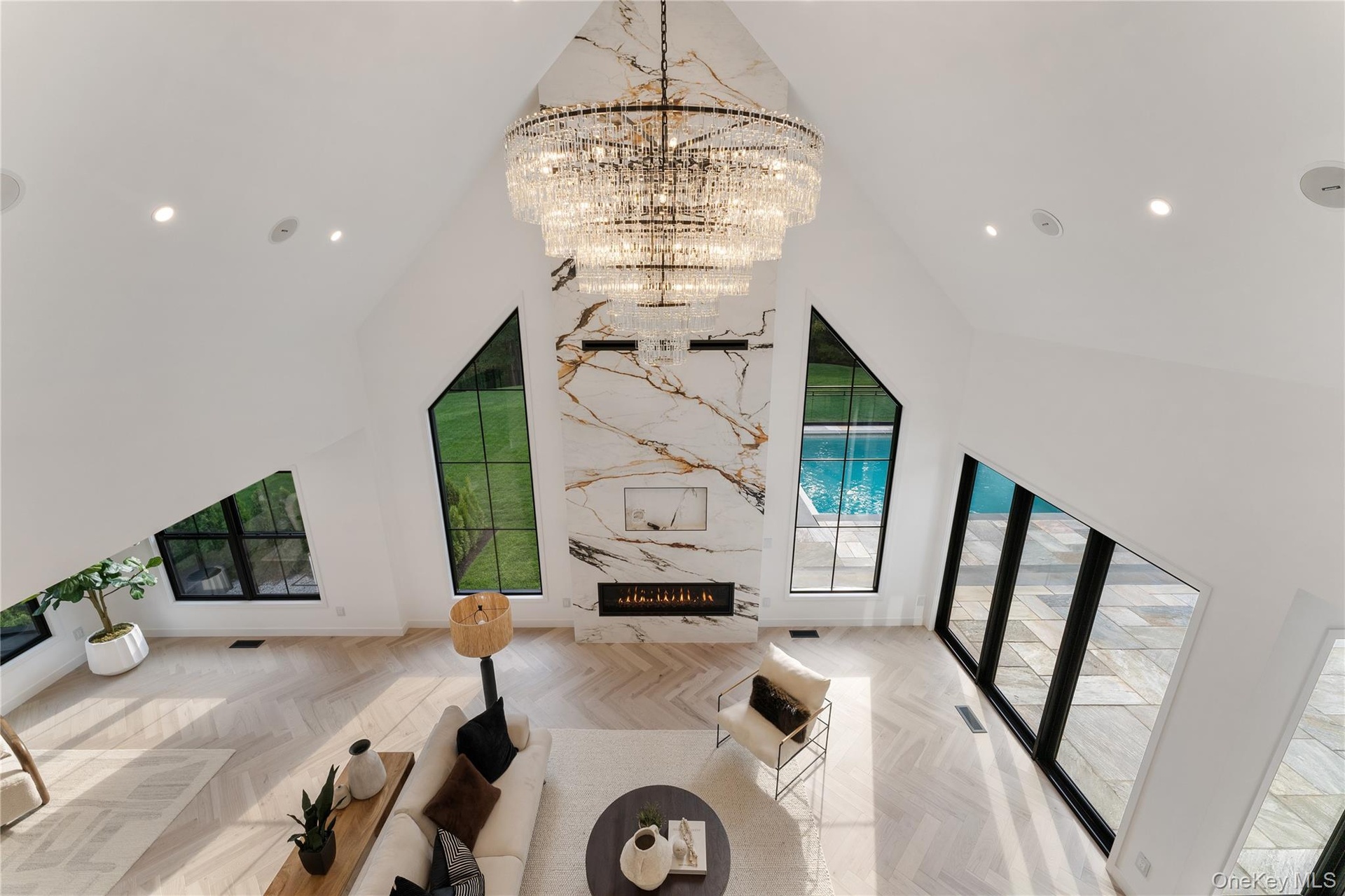 Living room with recessed lighting, a premium fireplace, high vaulted ceiling, and a chandelier