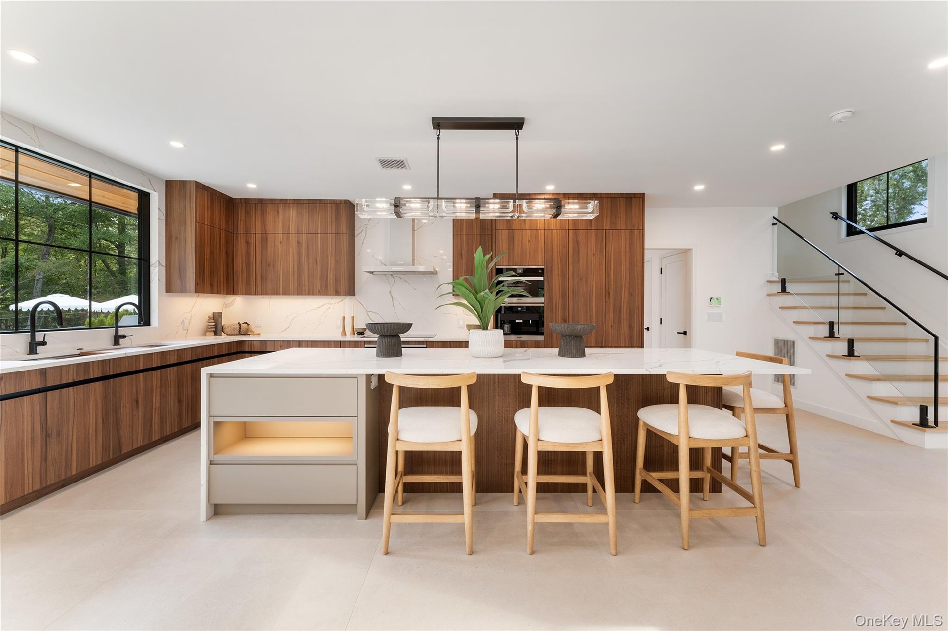 Kitchen featuring brown cabinetry, modern cabinets, decorative backsplash, light stone counters, and decorative light fixtures