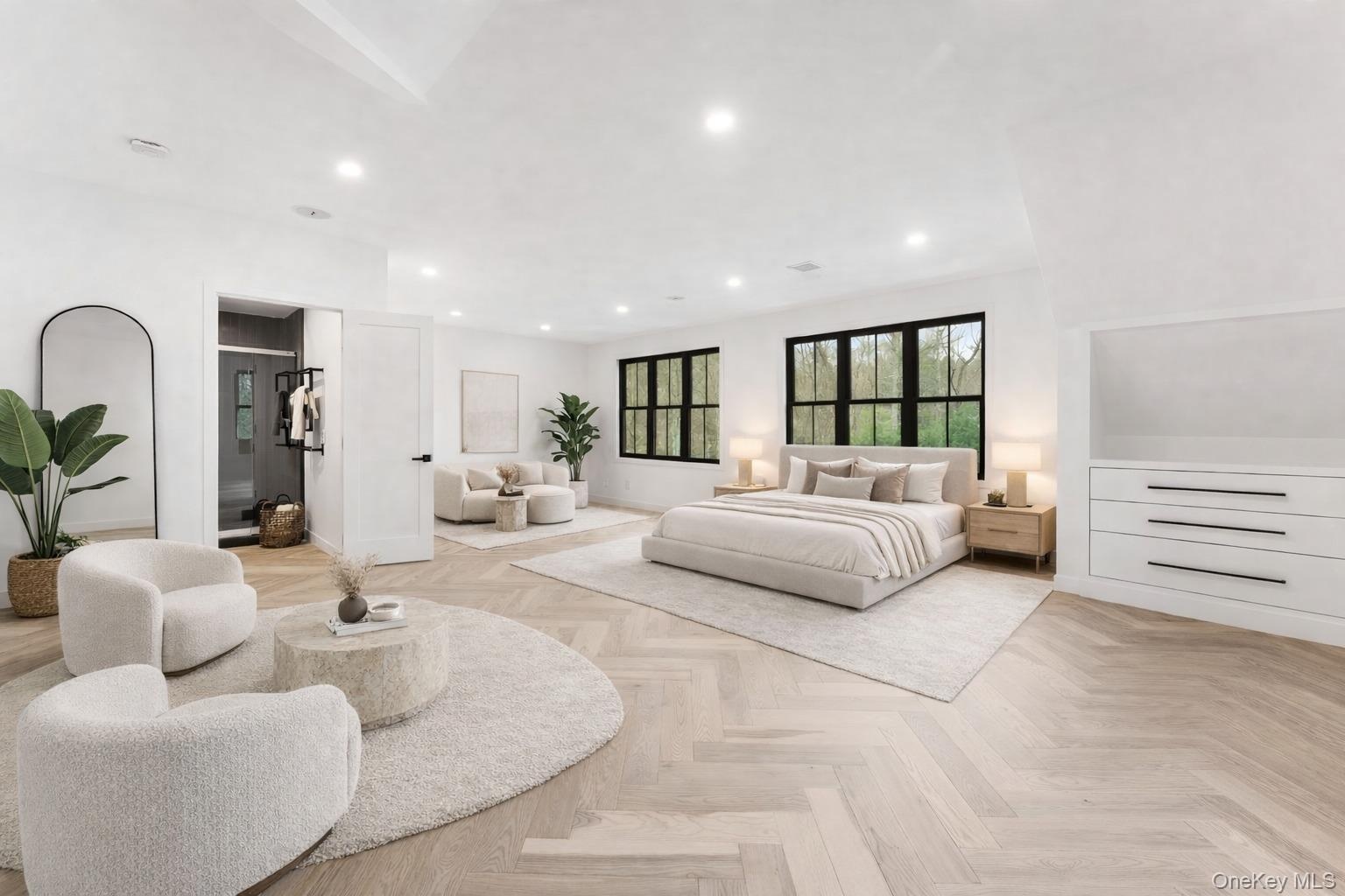 This spacious 2nd bedroom features herringbone pattern flooring, recessed lighting, and large windows with dark frames