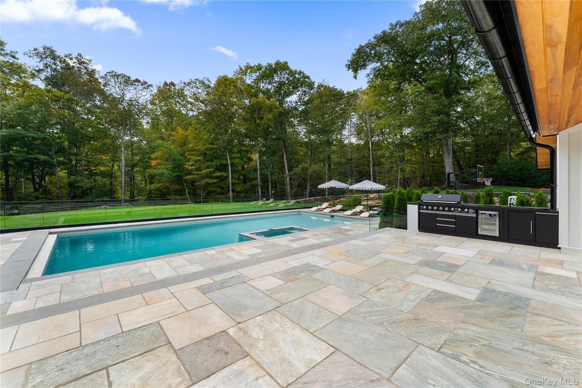 View of pool featuring a patio area with outdoor kitchen, a pool with connected hot tub, and exterior kitchen