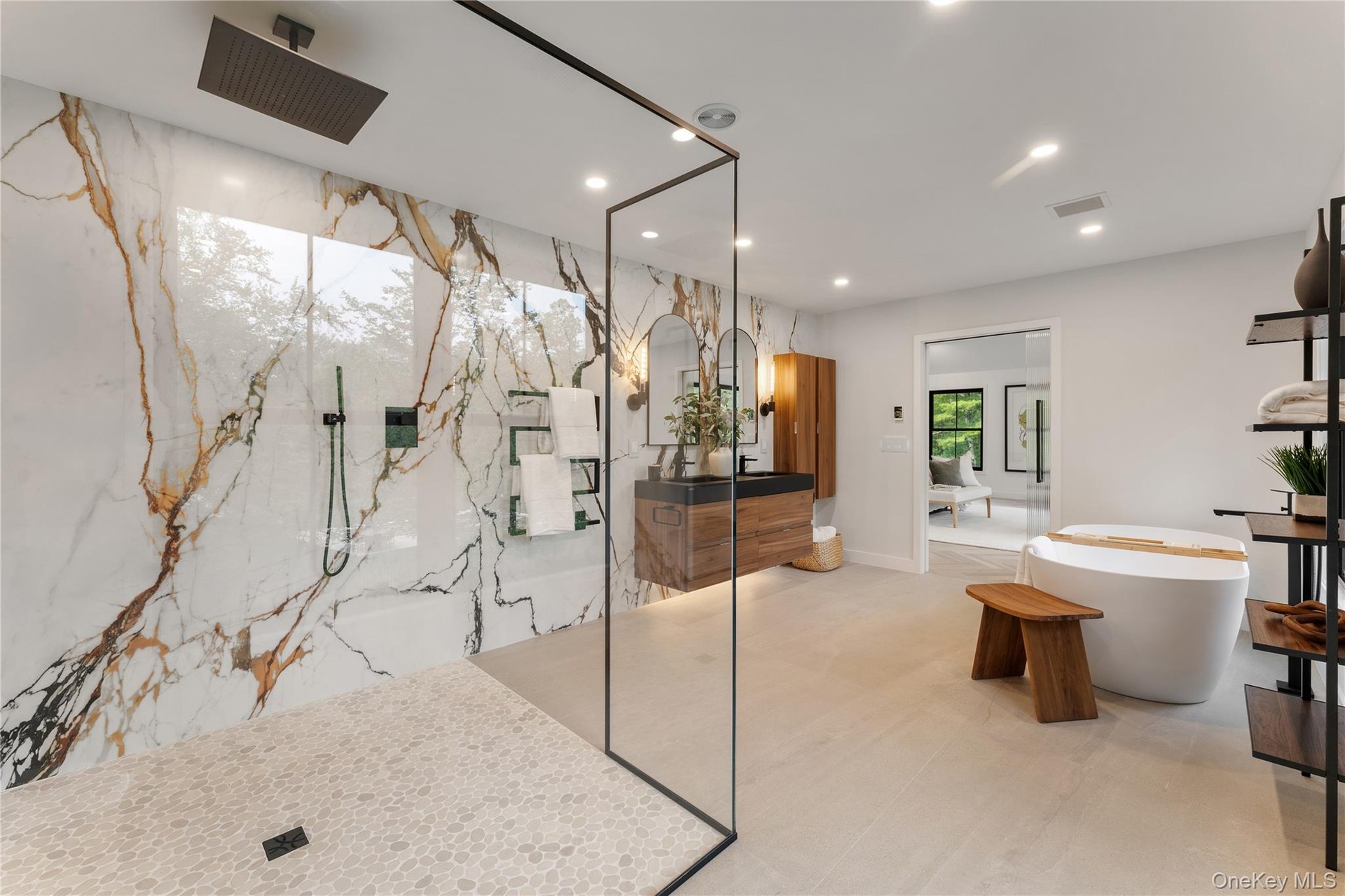 Bathroom featuring recessed lighting, a marble finish shower, a freestanding tub, and vanity