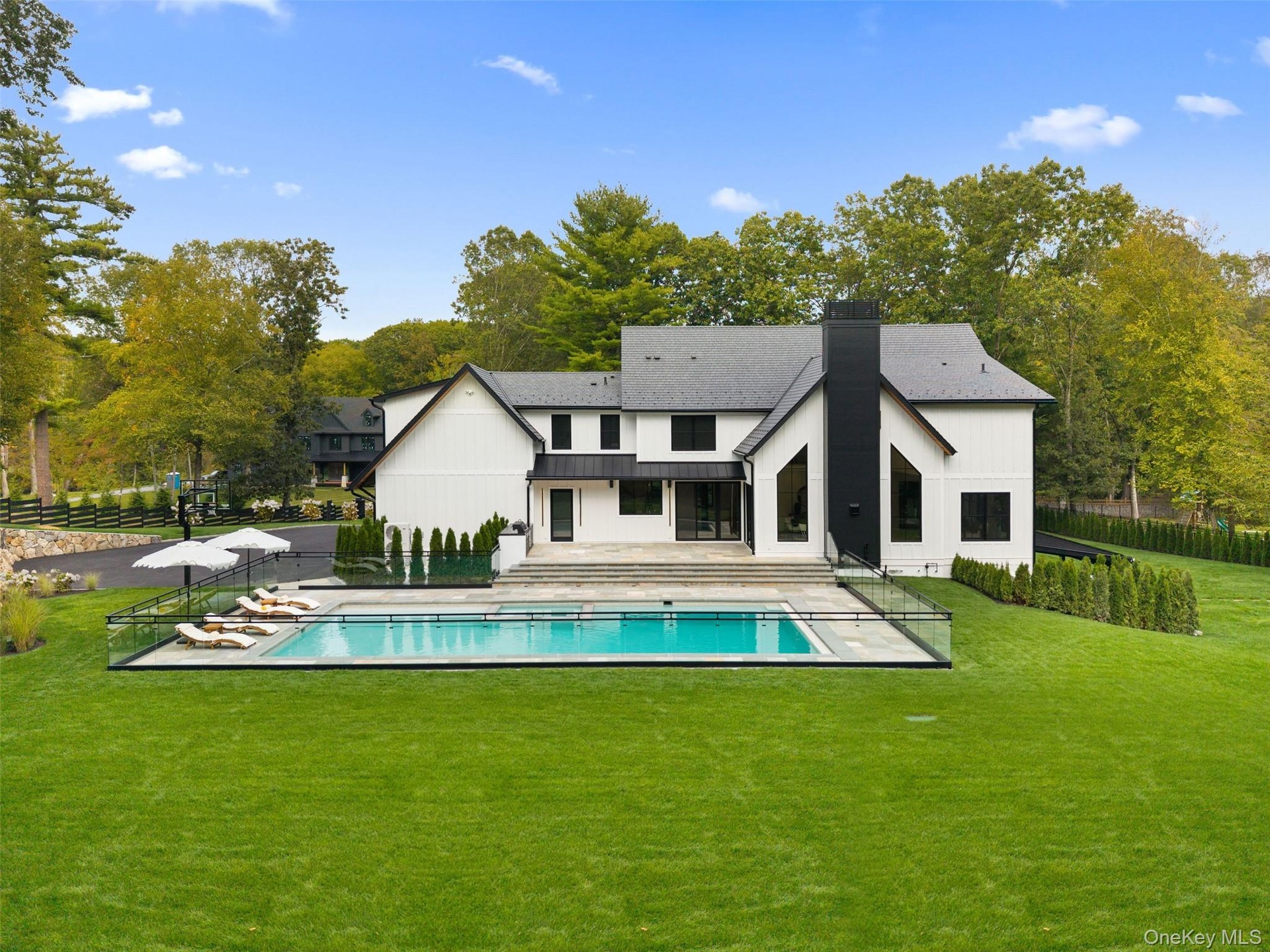 Back of property featuring a patio, a chimney, view of scattered trees, and a metal roof