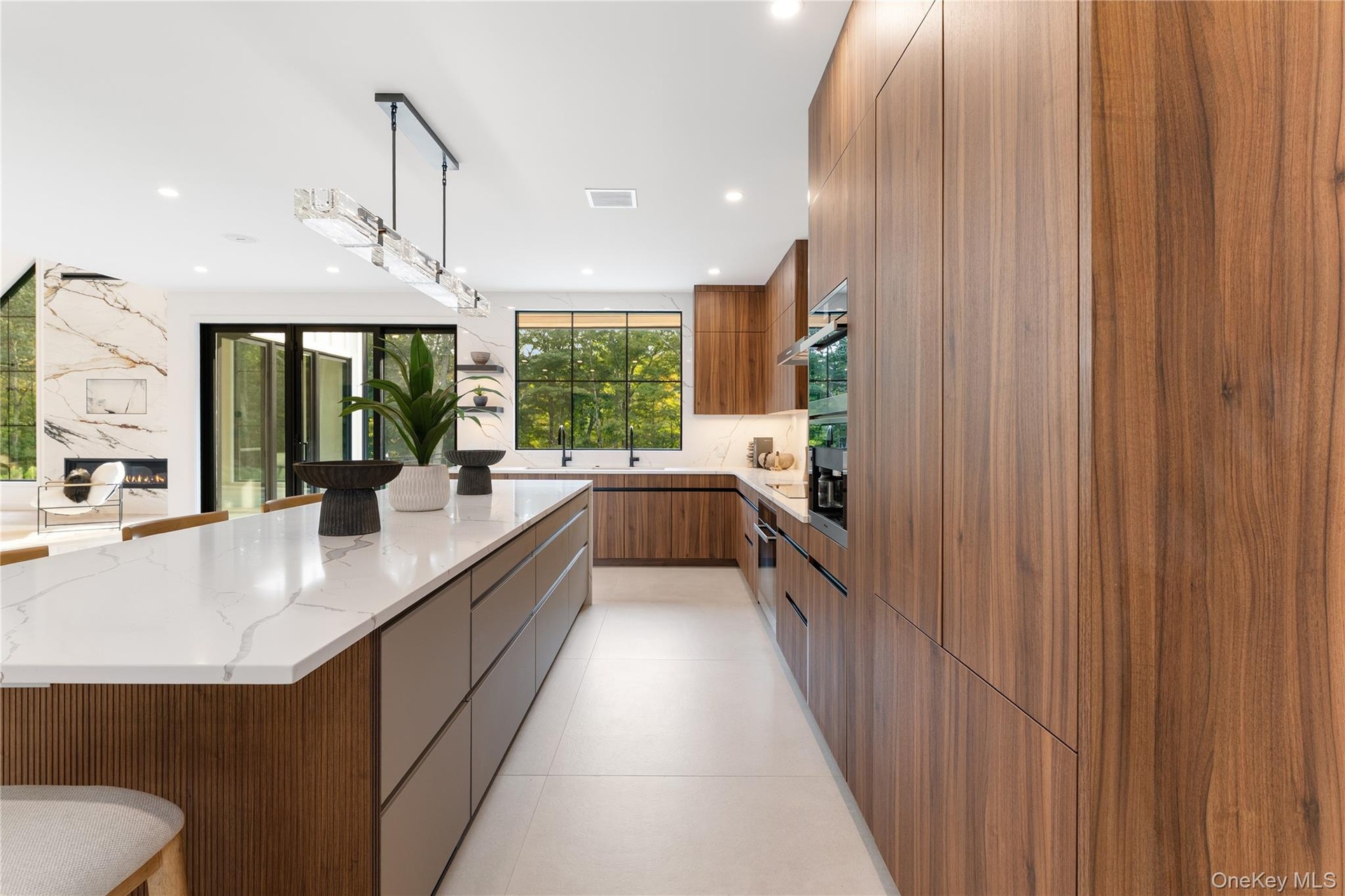Kitchen featuring modern cabinets, hanging light fixtures, light stone counters, a spacious island, and a kitchen bar