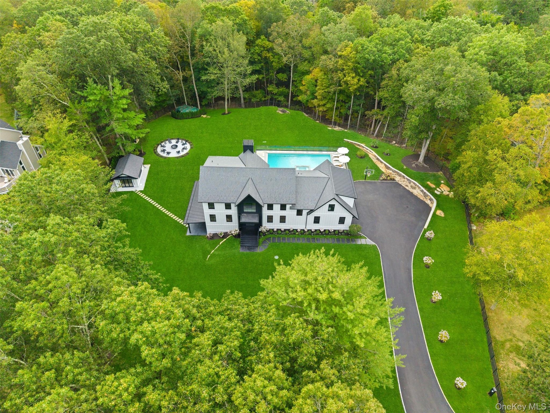 Aerial view of property and surrounding area with a heavily wooded area