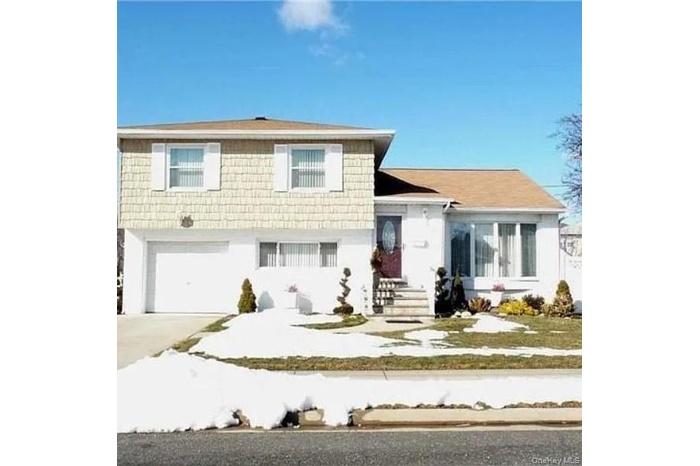 The property features a two-story design with light-colored siding on the upper level and a white lower level