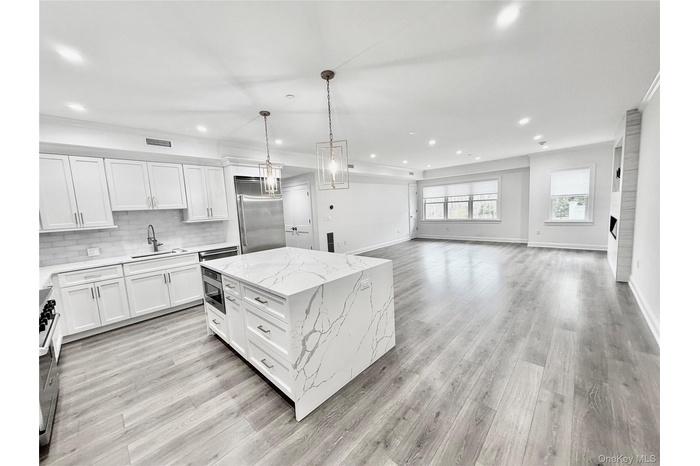 Kitchen with decorative light fixtures, white cabinets, recessed lighting, open floor plan, and a raised ceiling