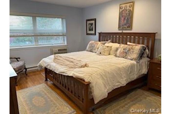 Hardwood flooring complemented by a A/C window unit and baseboard heating