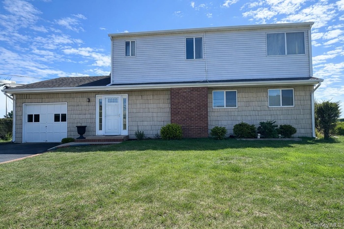 The property features a two-story exterior with a mix of siding and brick accents, a front lawn, and a paved driveway leading to an attached garage