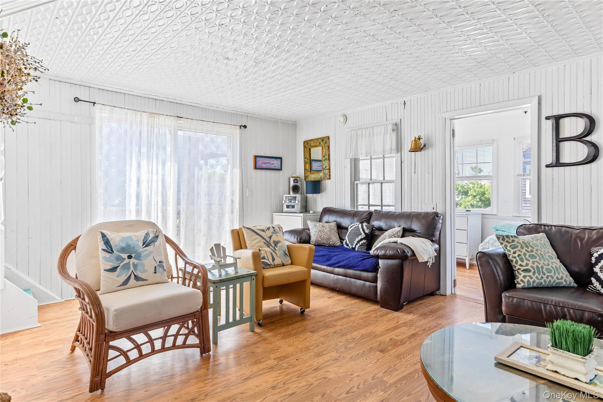 Living area featuring wood-finish flooring, white shiplap walls, and a white pressed-tin ceiling