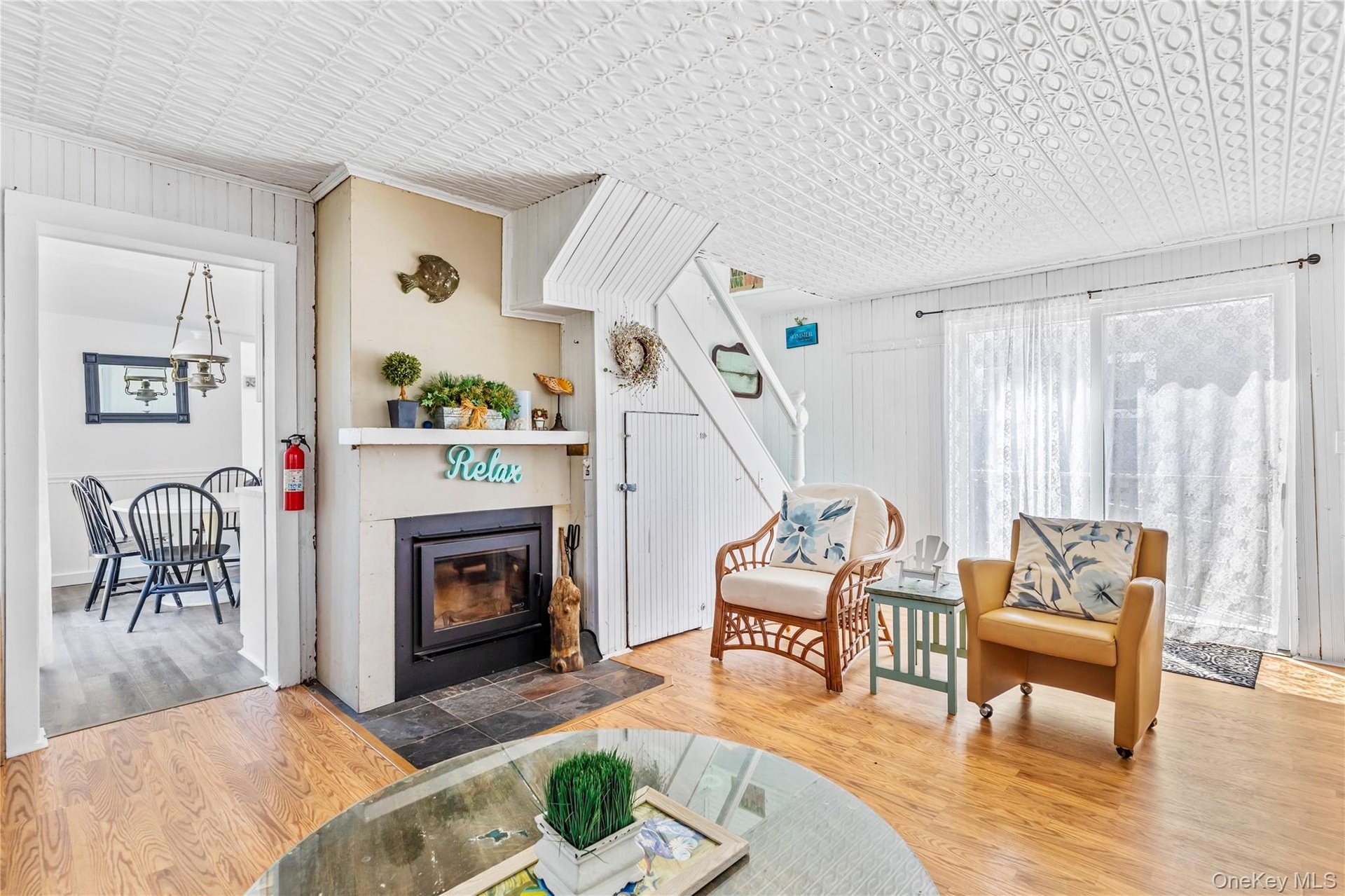 Living area featuring wood-finish flooring, a wood-burning fireplace with a slate hearth, and a white beadboard wall finish