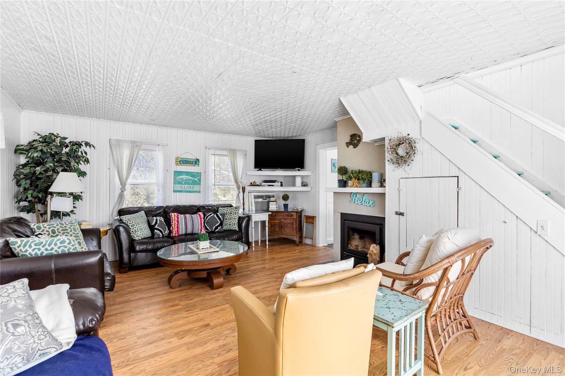 Open concept living space featuring wood-finish flooring, white paneled walls, and a decorative ceiling