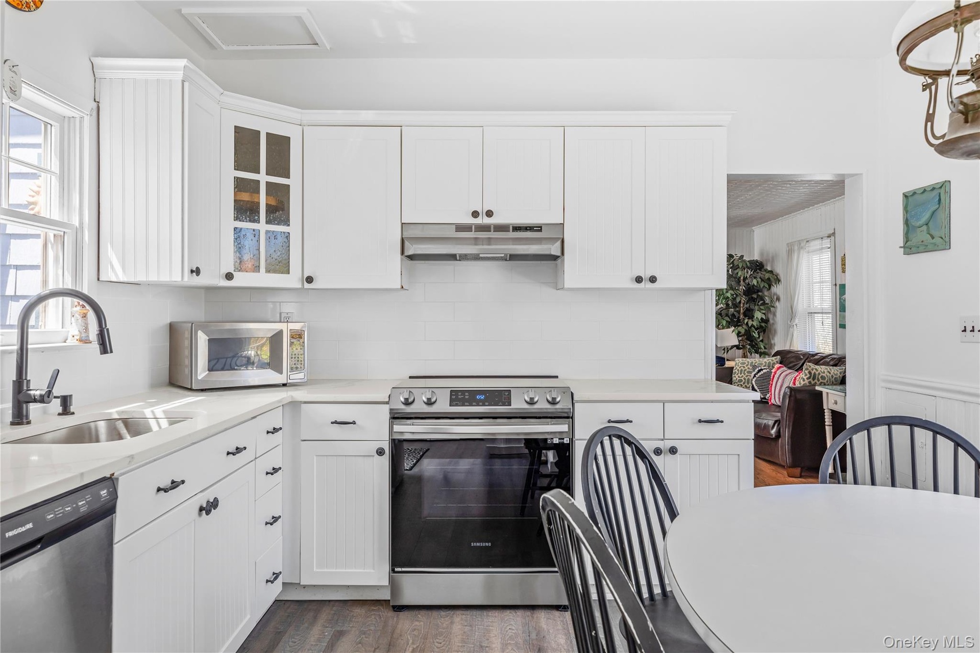Light-filled kitchen featuring white cabinetry, a stainless steel electric range, a stainless steel dishwasher, a single basin sink with a matte black