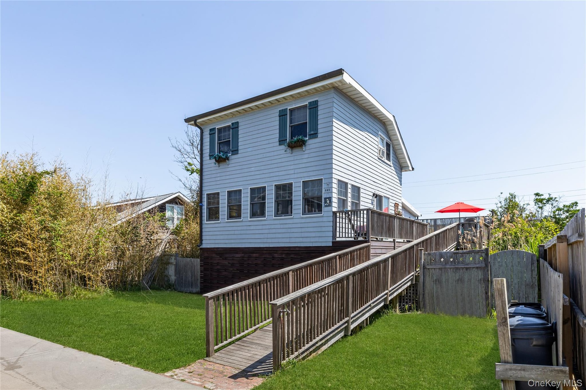 light blue siding, a multi-level wooden deck, and a wooden access ramp