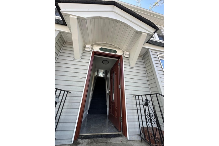 Entryway featuring a decorative overhang, light gray siding, and a rich wood-finish door with glass inserts