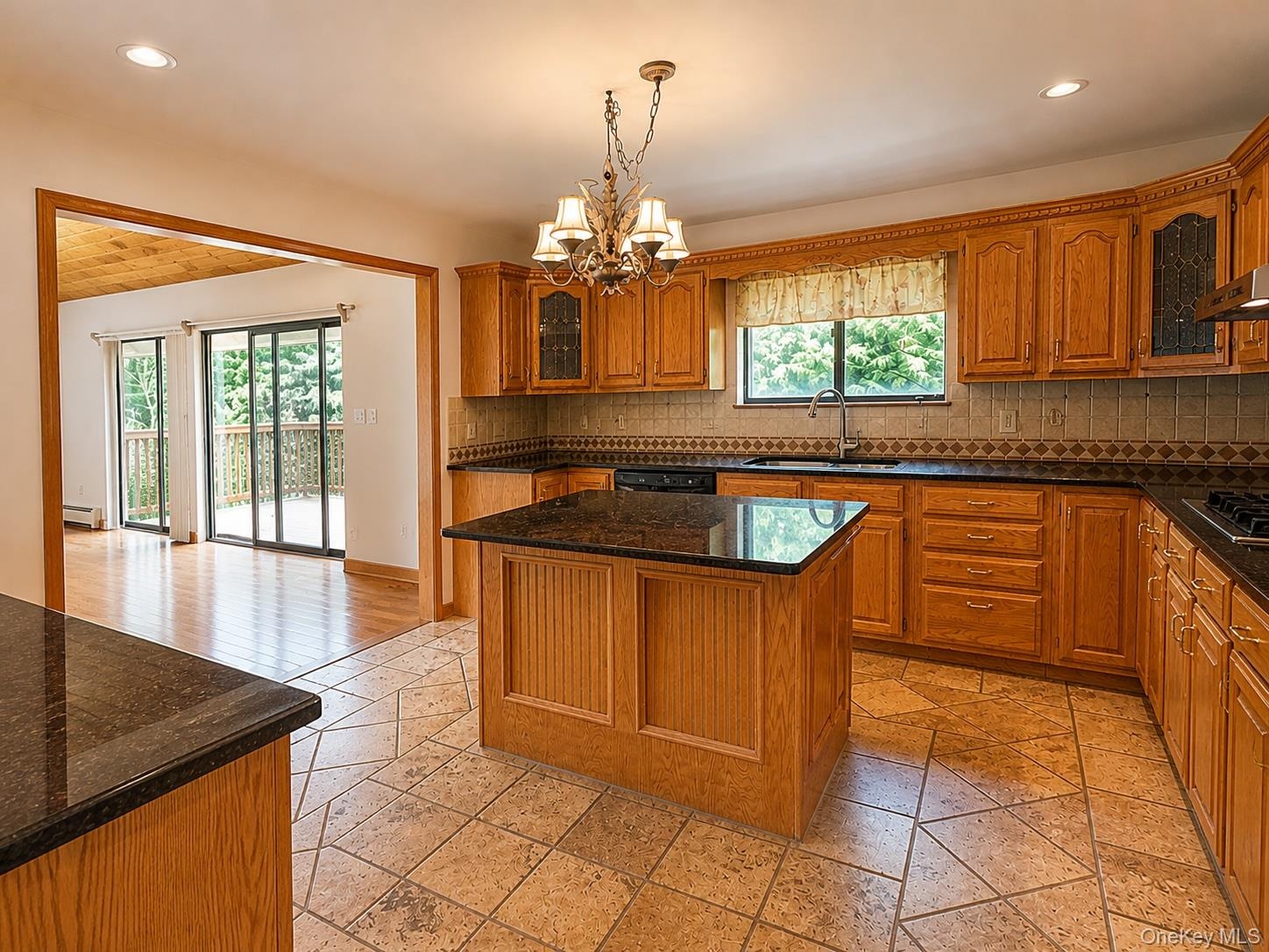 Kitchen featuring a central island with a dark countertop, extensive wood cabinetry, and a patterned tile backsplash