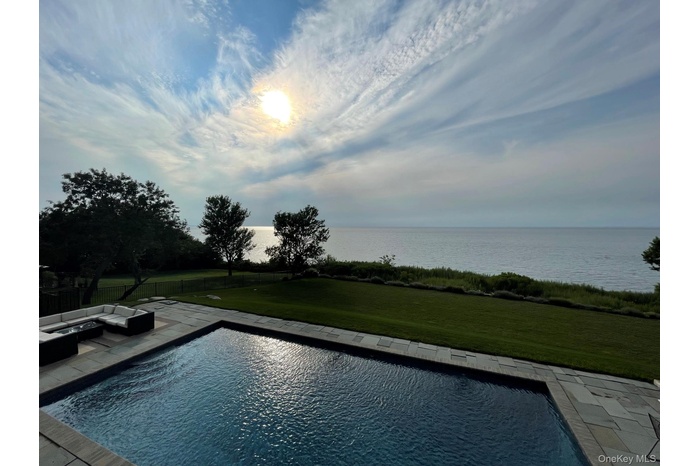 View of pool featuring a water view, a patio area, and a lawn
