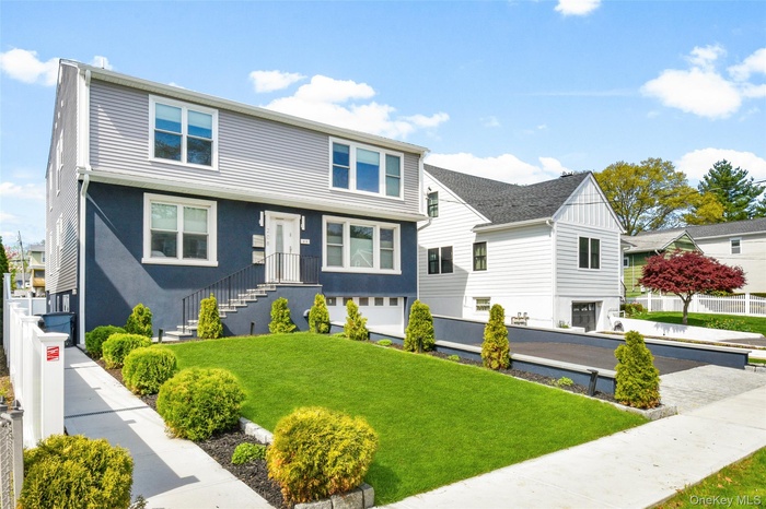 Contemporary residence featuring a stucco and siding exterior, manicured lawn, and a paved driveway