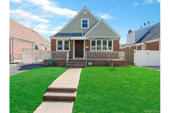 Brick facade residence featuring a front porch with decorative railing, bay window, and a gabled roofline
