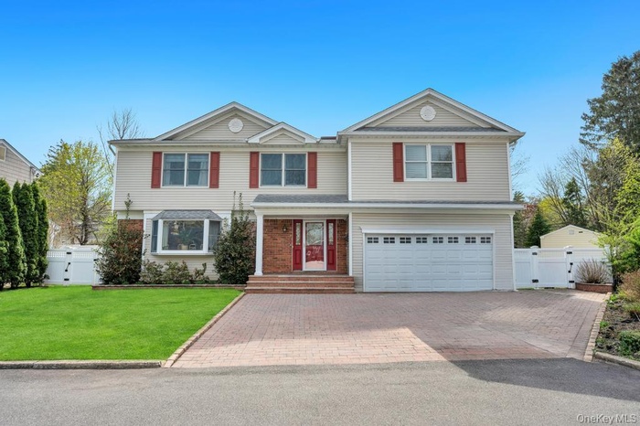 The property features a two-car garage, a paved driveway, and a well-maintained lawn