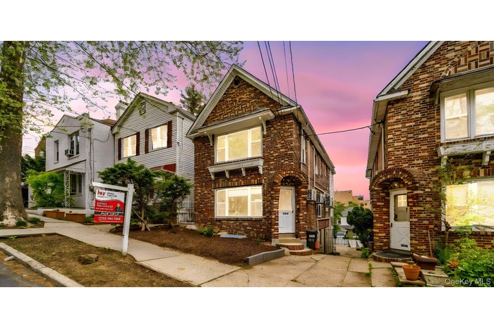 Brick facade featuring multiple levels, arched entryway, and prominent front windows