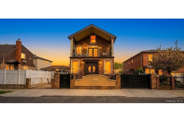 Brick facade residence featuring a prominent front entrance with dual doors, a second-story balcony with iron railings, and a gabled roofline. A.I Enc