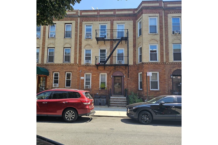 Brick and light-toned masonry facade building with a prominent fire escape