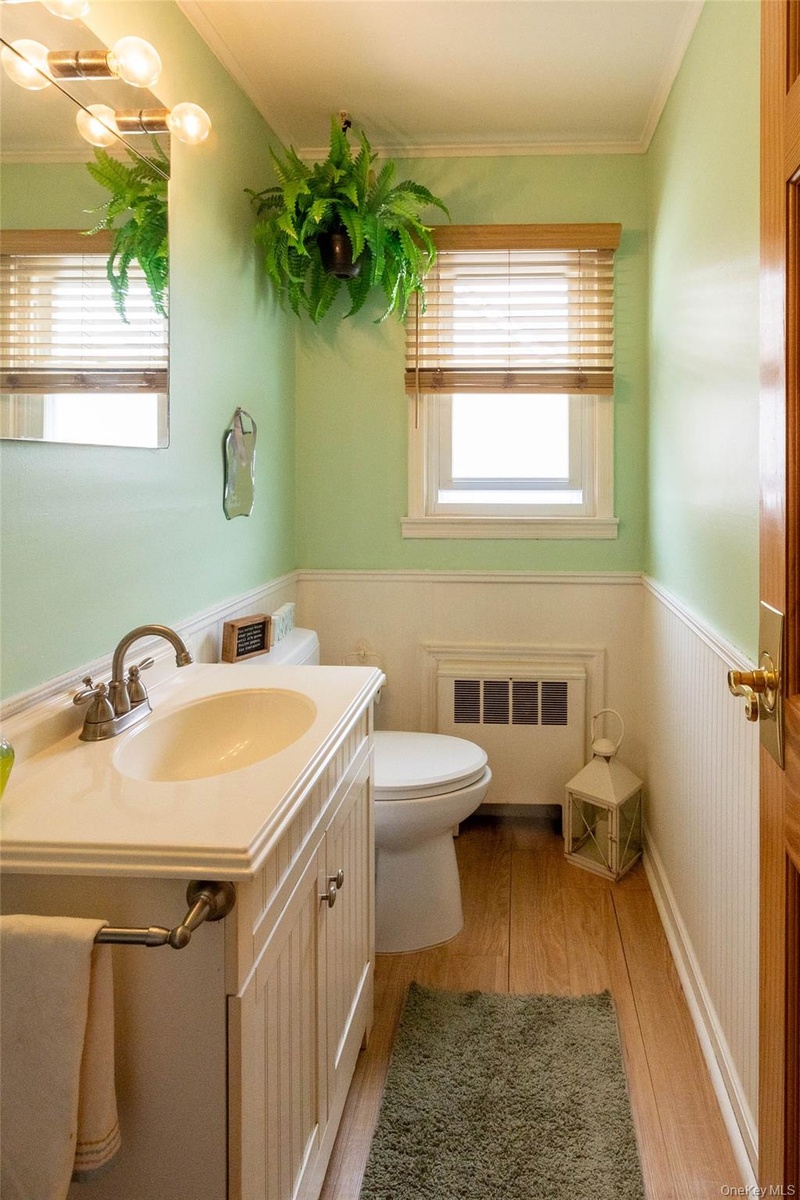 Bathroom featuring a vanity with an integrated sink, wood-finish flooring, and wainscoting