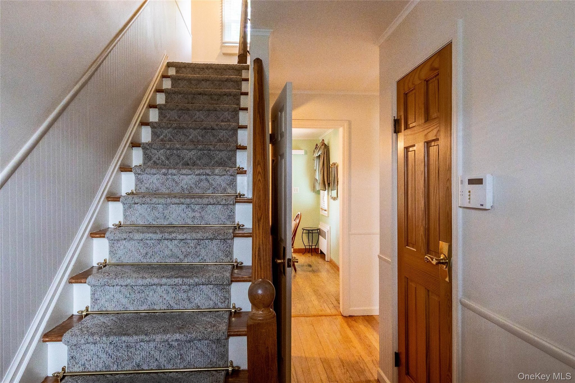 Hardwood staircase with carpet runner and brass stair rods