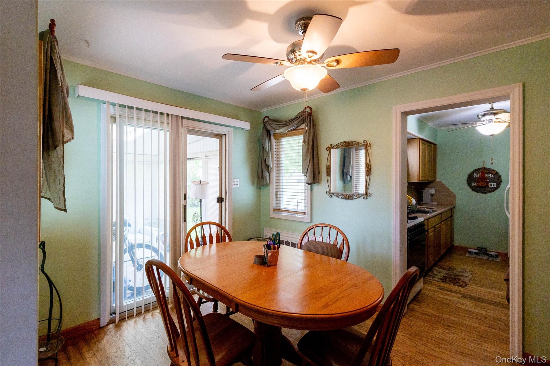 Dining area featuring wood-finish flooring, a ceiling fan with integrated lighting, and direct patio access through sliding glass doors