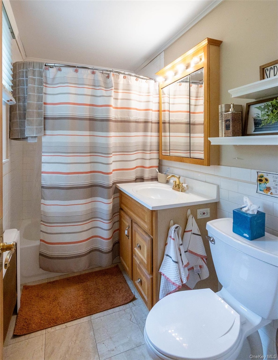 Bathroom featuring a single vanity with wood cabinetry, a white countertop, and a brass-finish faucet