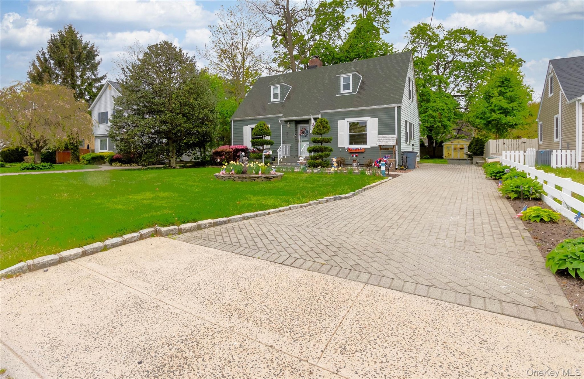 Cape Cod style home featuring a gabled roof, dormer windows, and white window shutters