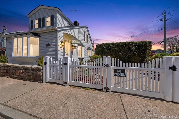 Traditional clapboard siding exterior with a white picket fence and dual gates
