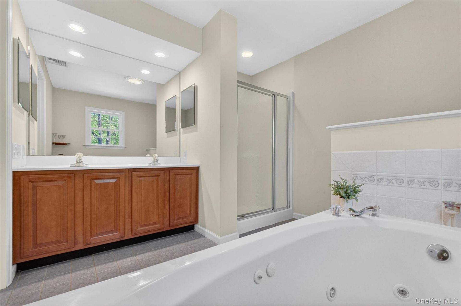 Large primary bathroom with Jetted tub, shower and double vanity sink.