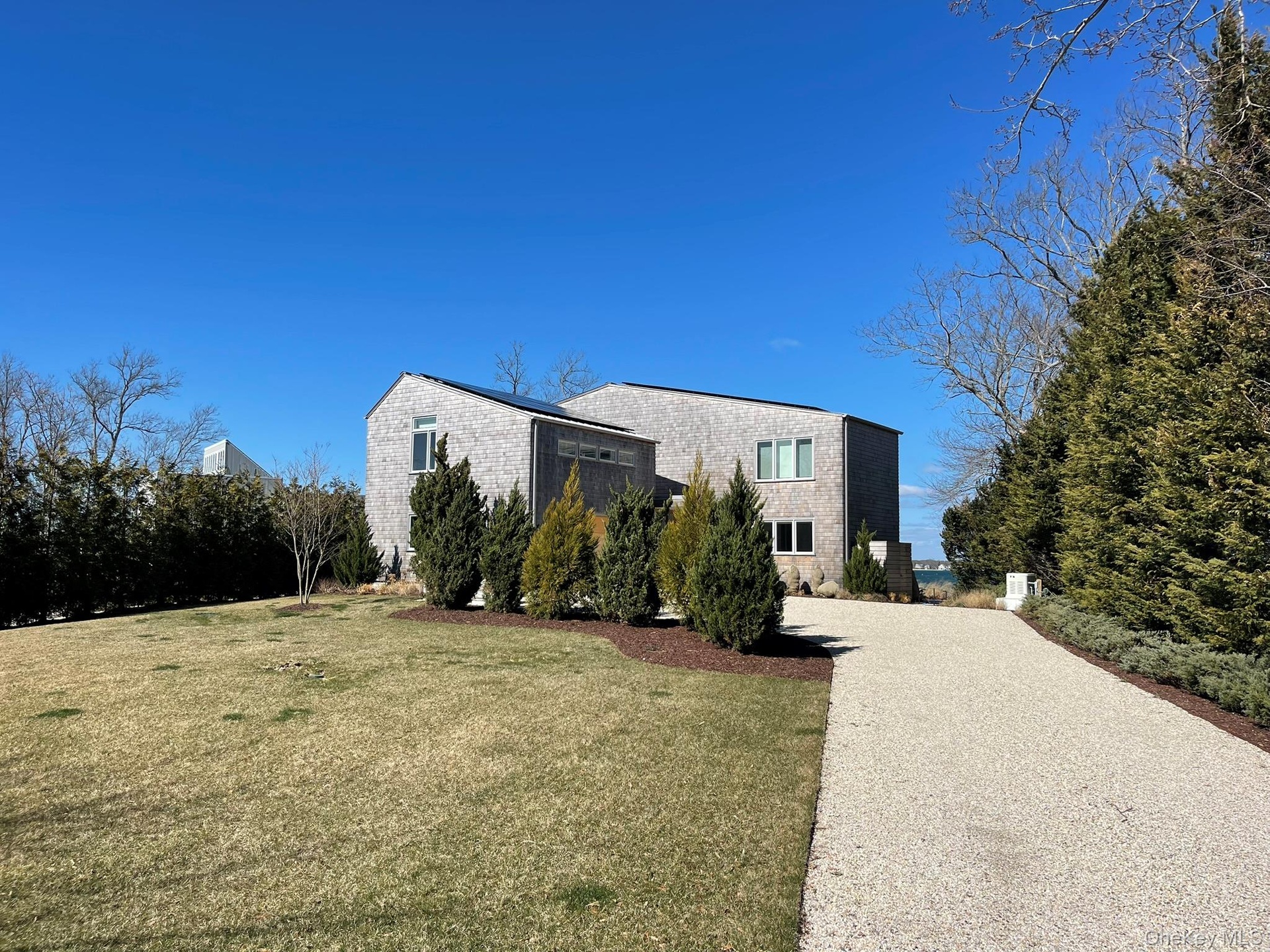 View of property exterior with a lawn and gravel driveway