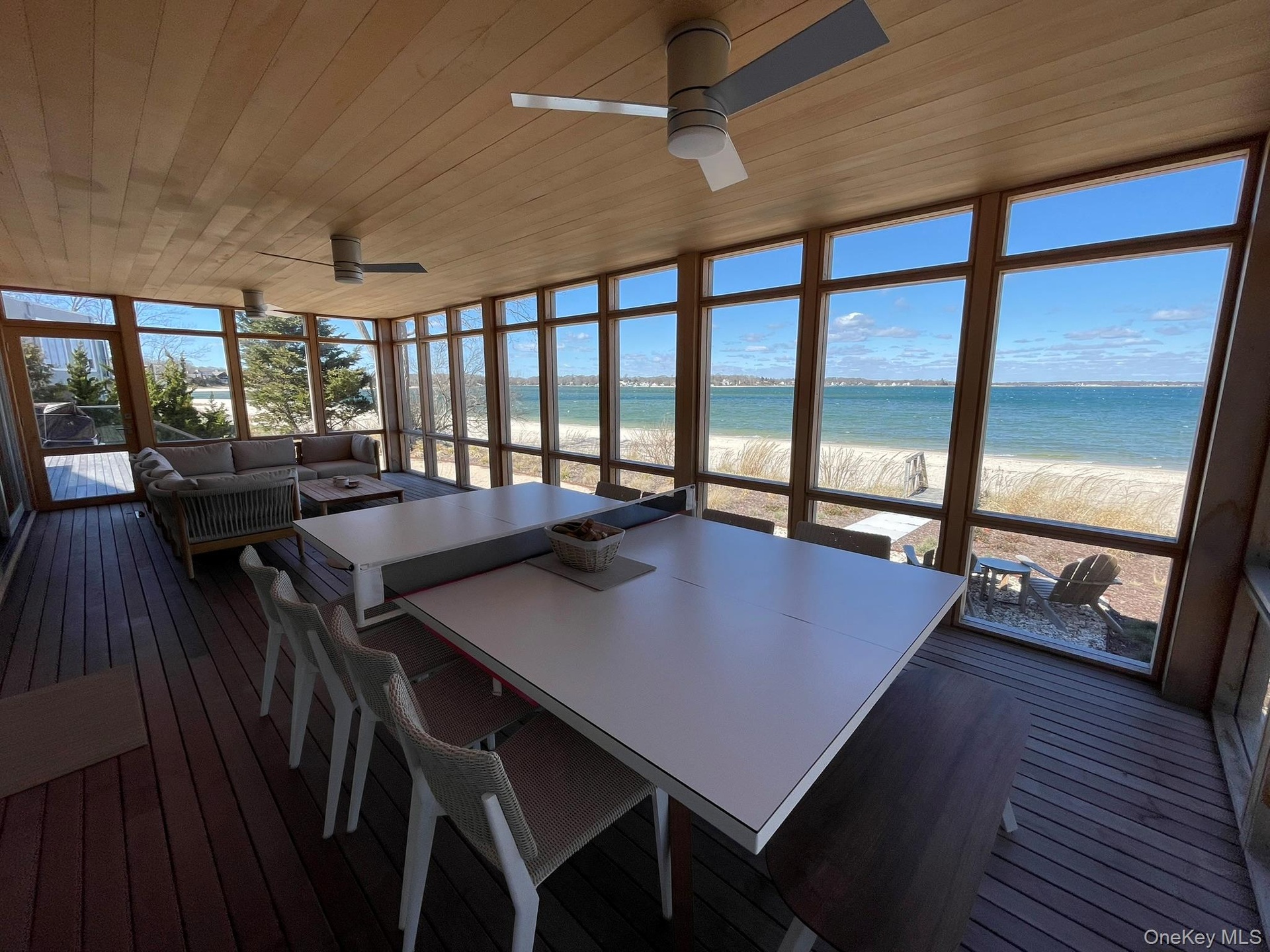 Sunroom with a beach view, ceiling fan, and outdoor dining area