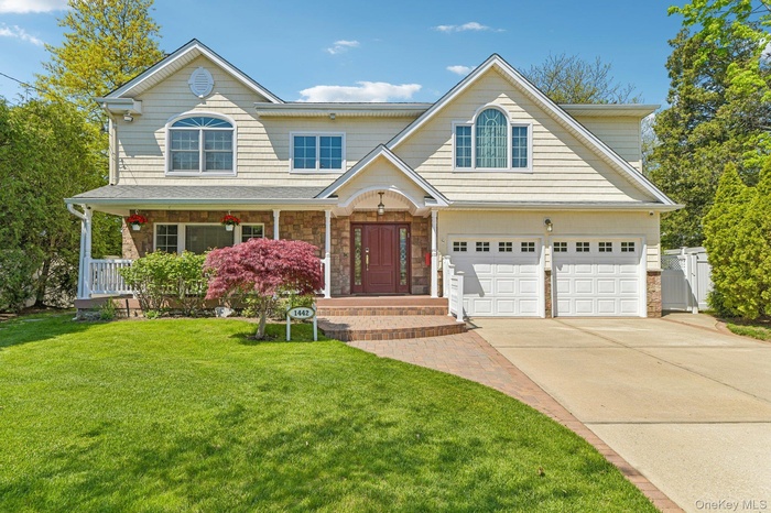 Two-story residence featuring light-colored siding, a covered front porch, and an attached two-car garage