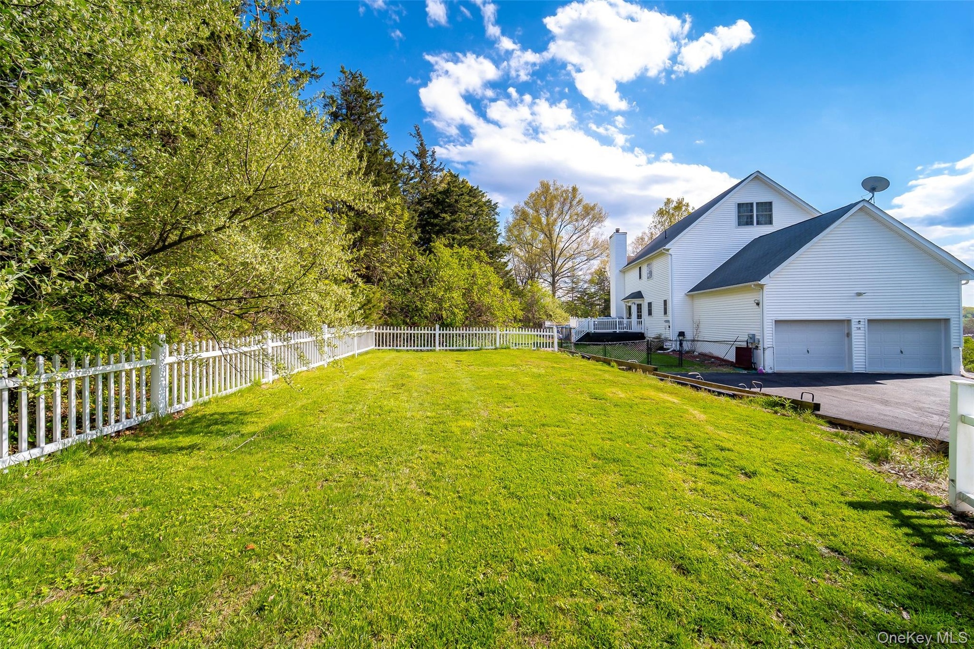 Expansive grassy yard area with a white picket fence
