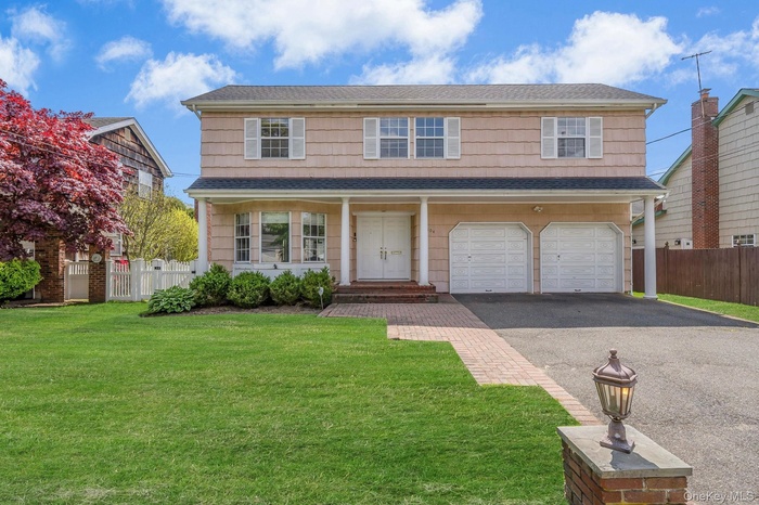 Beautiful two-story  Colonial residence, a manicured front lawn, and a brick paver walkway