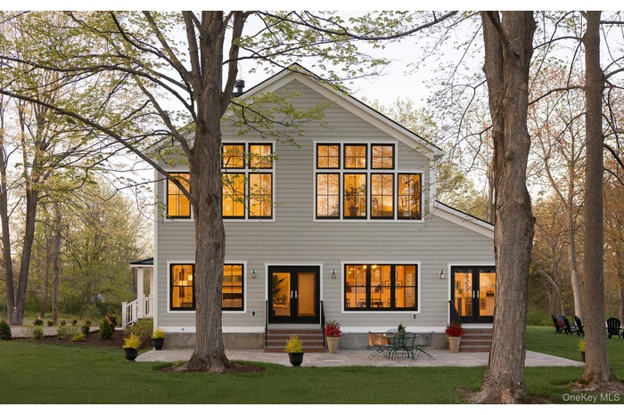 Southern side of the home with patio, two sets of patio doors, and extensive windows