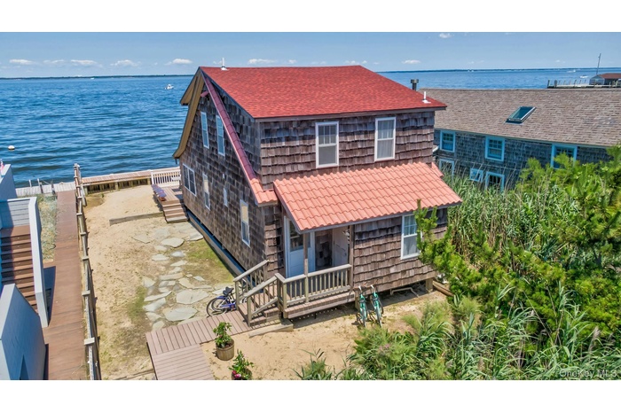 Waterfront residence featuring shingle siding and a red roof
