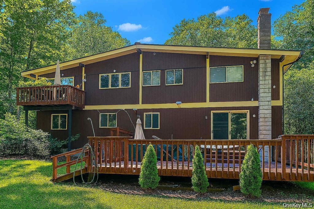 Multi-level exterior featuring brown vertical siding, yellow trim, and multiple windows