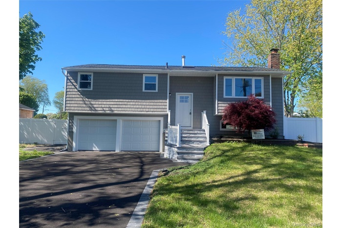 Split-level residence featuring gray shake siding and a two-car garage