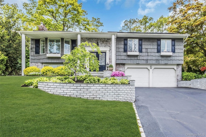 Split-level residence featuring a two-car garage, bay window, and a stone facade